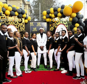 An image of Moya David posing with his staff at the grand opening of his newest venture, Moya City Spa.
